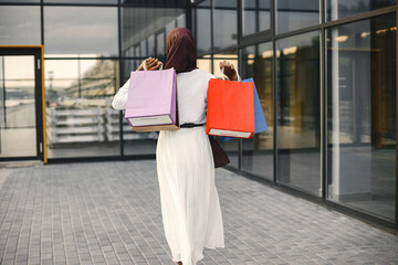 Backside photo of arabic woman wearing hijab standing with shopping bags