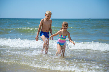 Naklejka premium Girl and boy of having fun in water on beach and splashing