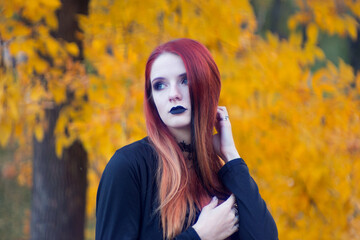 beautiful fashionable young girl witch model stands outdoors in the forest in autumn by the river, pale, vampire, goth