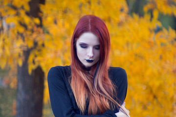 beautiful fashionable young girl witch model stands outdoors in the forest in autumn by the river,...