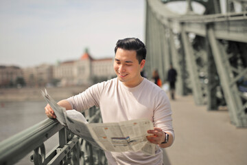 young man reads a newspaper in the city