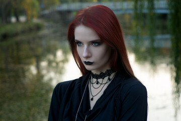 beautiful fashionable young girl witch model stands outdoors in the forest in autumn by the river,...