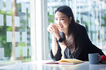 Obraz premium Beautiful Asian woman work at a coffee shop with a Tablet, smile and listening to music happily.