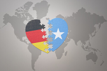 Fototapeta premium puzzle heart with the national flag of somalia and germany on a world map background. Concept.