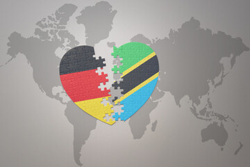 puzzle heart with the national flag of tanzania and germany on a world map background. Concept.