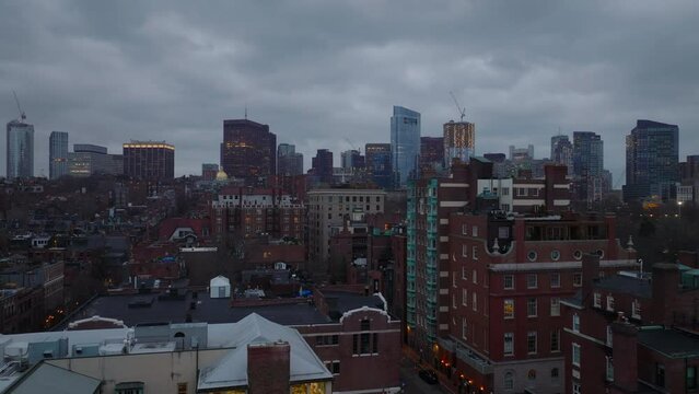 Residential brick buildings in Back Bay borough and downtown high rise office towers against overcast sky at twilight. Boston, USA