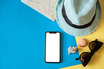 Travel kit with hat, travel card, smartphone and sunglasses on a blue background.Travel flat lay