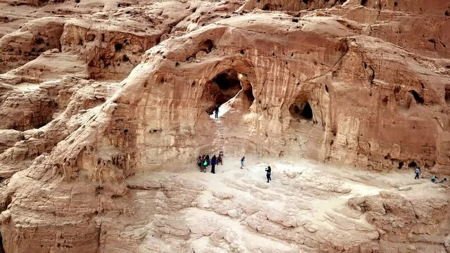 Group of tourists takes pictures at The Arches in the dry Timna Park in the red canyon in the Negev desert in southern Israel. High angle drone panning shot