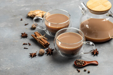 Glass cup of traditional indian masala chai tea with milk and spices on gray background. banner,...