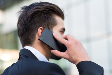 Young businessman talking on the phone in front of corporate office building