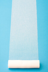 Sterile bandage roll unwound on blue background.