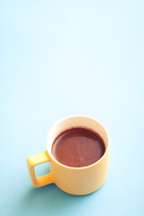A cup of hot coffee in pastel colors. Turkish coffee in a yellow mug on blue background.