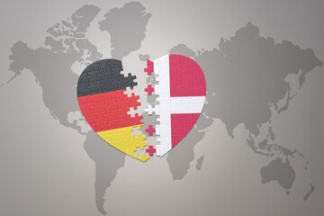 puzzle heart with the national flag of denmark and germany on a world map background. Concept.