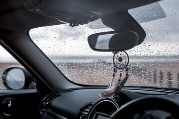 Dream catcher hanging from rear view mirror in car on wet beach