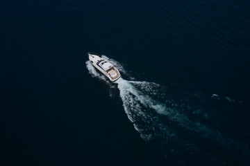 large yacht top view. Boats top white waves on dark water. Aerial view of a boat in motion in dark water. Large boat at high speed on dark blue water and top view.