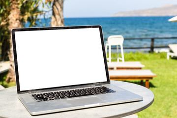 White laptop and sunglasses laying on sunbed at beach on bright sunrise sea background - Powered by Adobe
