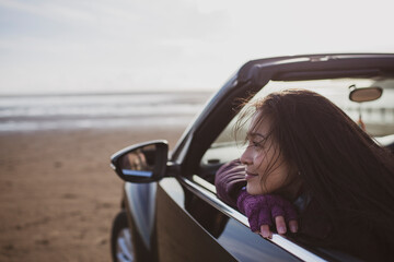 Serene woman in convertible on winter beach