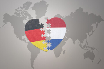 puzzle heart with the national flag of netherlands and germany on a world map background. Concept.