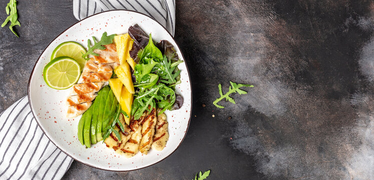 Buddha bowl, Grilled chicken breast, halloumi, pineapple, avocado, green rocket salad, lime and olive oil. healthy and balanced food. Long banner format. top view