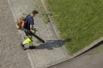 Jardinier en train de nettoyer une all&eacute;e d'un espace vert