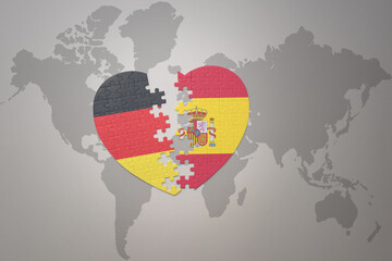 puzzle heart with the national flag of spain and germany on a world map background. Concept.