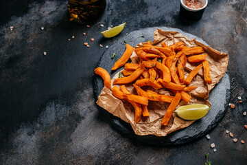 Sweet potato fries with herbs on dark background. Long banner format. top view