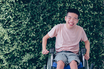 Young man with disability with happy face by with cheerfulness in nature green background, Teenager boy sitting with tray for activities on wheelchair, Good mental health and positive picture concept. - obrazy, fototapety, plakaty