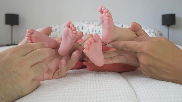Parents touching baby's feet. Newborn twins in bed with mom and dad, close up