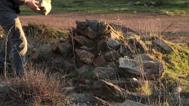 Young man trips and almost falls while carrying a big rock outdoors.
