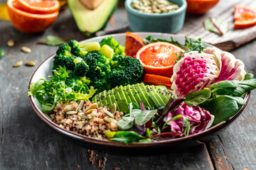 Quinoa vegetable vegetarian buddha bowl avocado, blood orange, broccoli, watermelon radish, spinach, quinoa, pumpkin seeds. top view