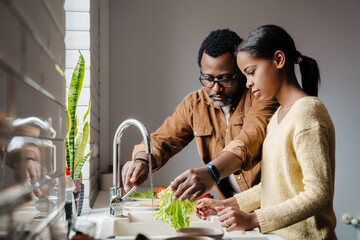 Black man making sandwiches with his daughter at home