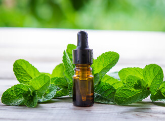 Bottle with essential oil and mint isolated on a light background.