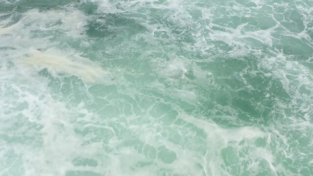 Cinematic drone shots of the Icelandic sea waves crashing over rocks. Tight shot showing stunning water colour.