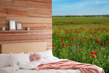 Comfortable bed with soft pillows in in poppy field on sunny day