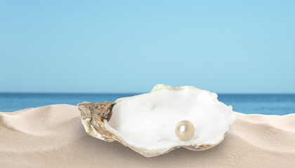 Open oyster shell with white pearl on sandy beach near sea