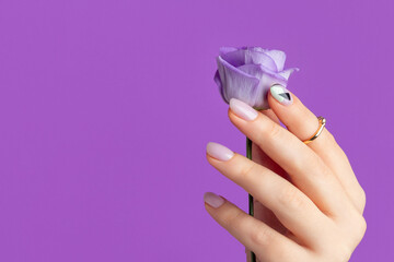 Beautiful womans hand with spring summer design on violet background. Manicure, pedicure beauty salon concept