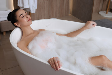 Woman taking bath with shower gel indoors