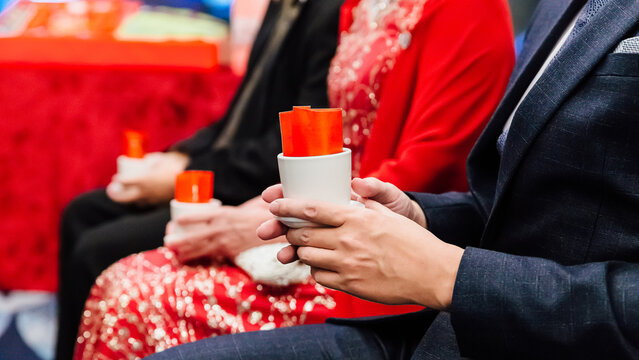Chinese wedding custom, row of hands holding cups with red envelopes