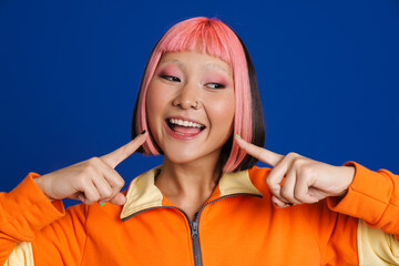 Asian girl with pink hair and piercing pointing fingers at her smile