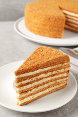 Slice of delicious layered honey cake served on grey table, closeup