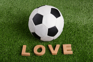 Soccer ball and word Love on green grass