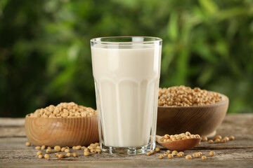 Glass with fresh soy milk and grains on white wooden table against blurred background