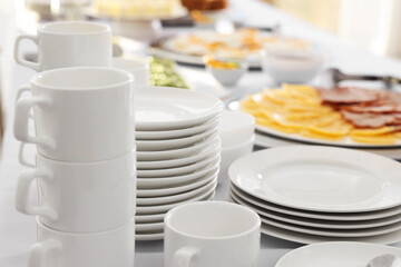 Clean dishware and different meals for breakfast on white table indoors. Buffet service