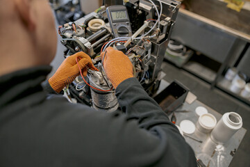 Professional worker fixing coffee machine in workshop