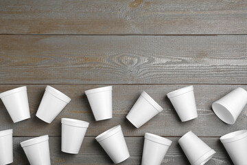 Many white styrofoam cups on wooden table, flat lay. Space for text