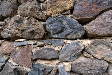 Stone wall with abstract pattern under sunlight.