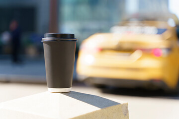 Takeaway coffee in a paper cup. Hot drink to go on the background of a busy city street. Paper cup mockup