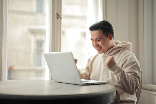 young man rejoices happy in front of a computer