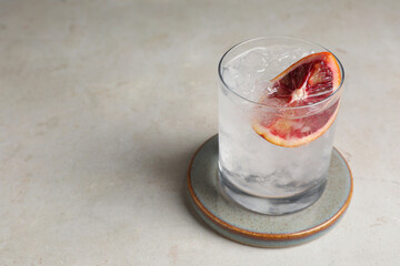 Delicious refreshing drink with sicilian orange and ice cubes on light table. Space for text