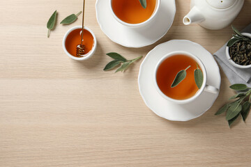 Flat lay composition with aromatic sage tea on wooden table. Space for text